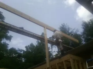 Carpenter setting a ridge beam over a new addition frame — Ice Dam Removal by Roofing Brothers in Camanche