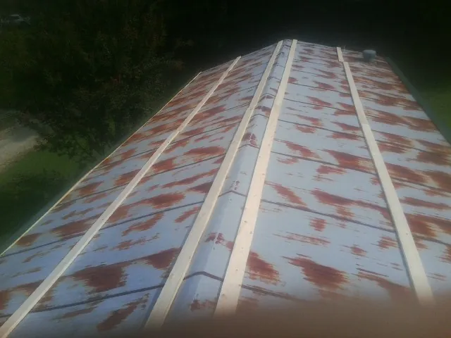 Rusted metal roof panels with new wood purlins before replacement — Storm Damage Roof Repair in Camanche by Roofing Brothers