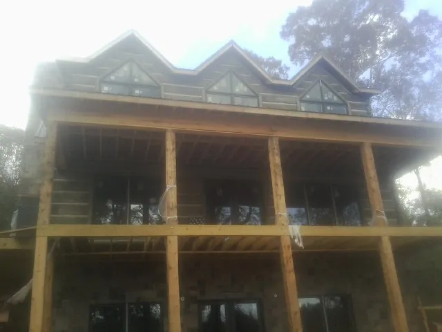Dormers and porch framing on a large log home under construction — Roof Coating work by our crew in Camanche