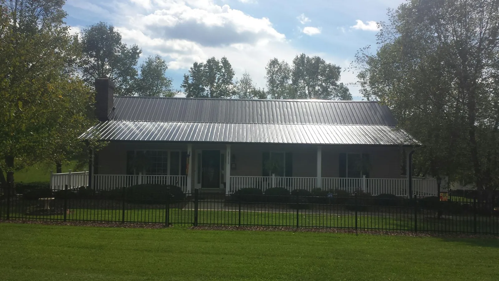 Gray metal roof on a brick ranch with a full width front porch — Gutter Guard Installation work by our crew in Camanche