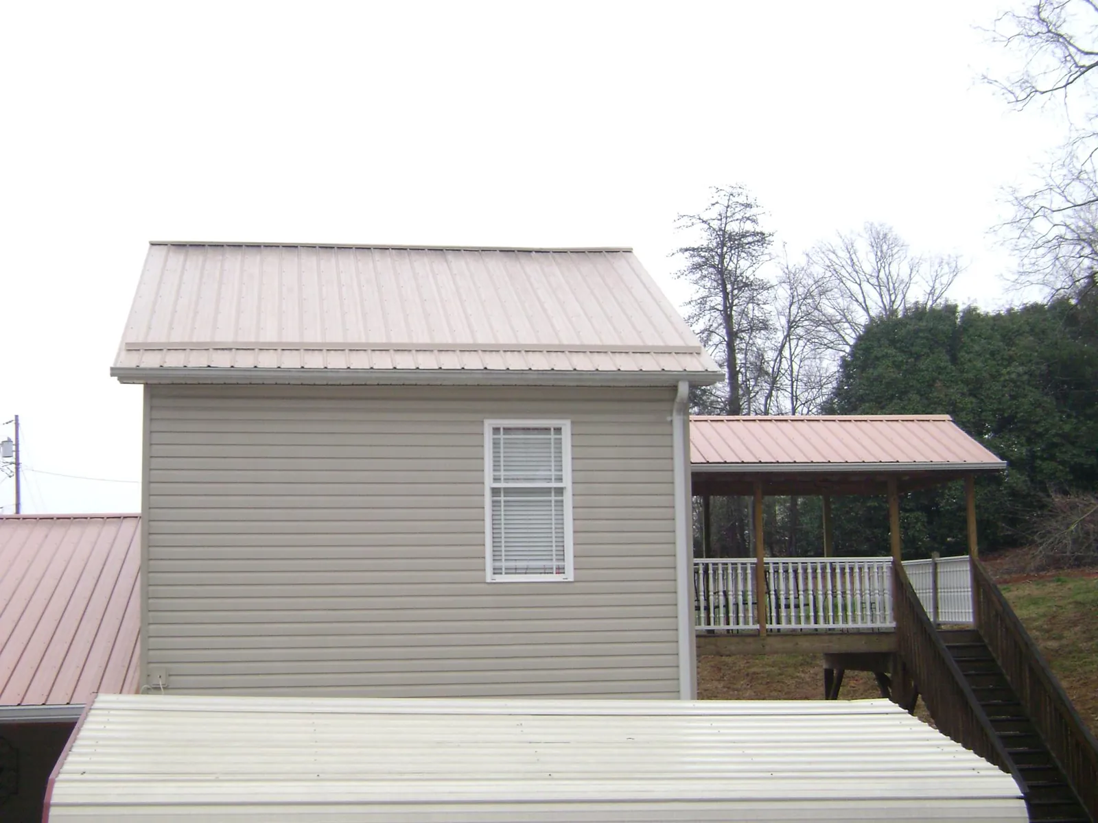 Tan metal roofs on a two story addition and attached porch, from a Roof Replacement job in Camanche
