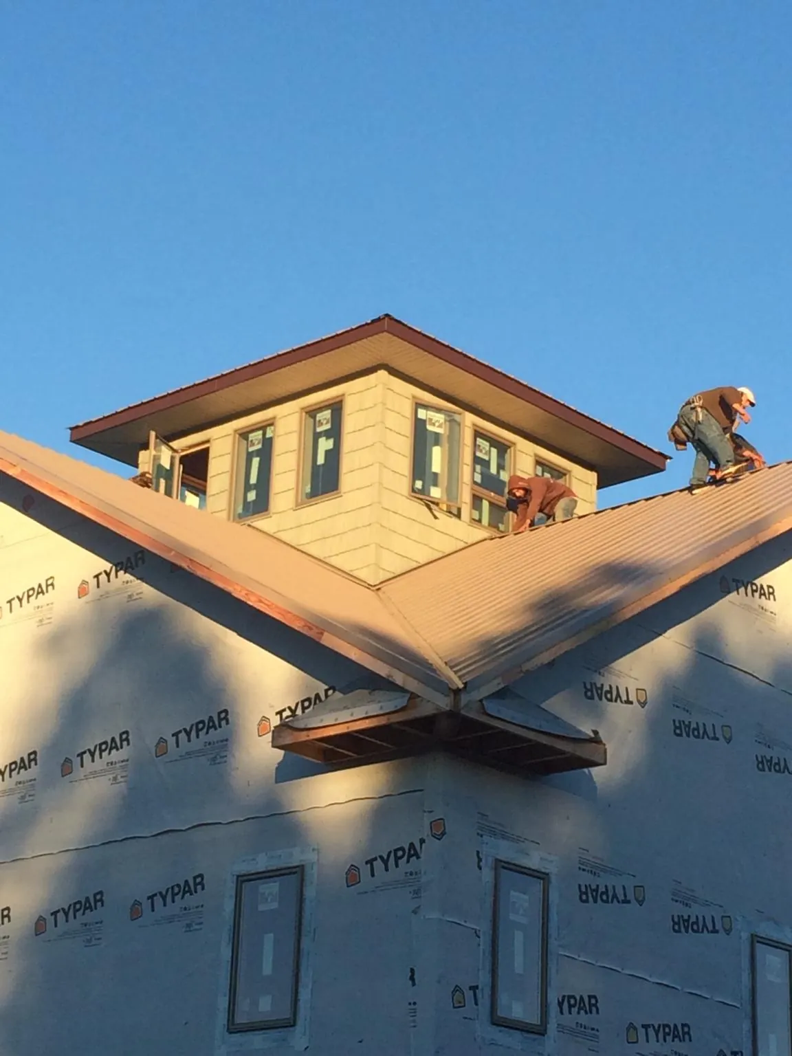 Roofers working around a rooftop cupola on a new metal roof at sunset — Roof Waterproofing in Camanche by Roofing Brothers